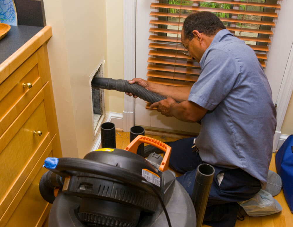 Worker with vacuum during residential duct cleaning